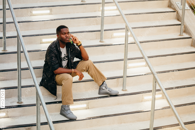 View of man sitting on stairs and talking on mobile phone