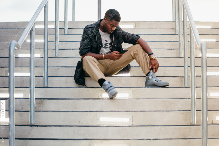 View of man sitting on stairs with mobile phone