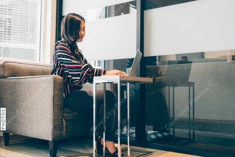 Young businesswoman sitting on couch and working on laptop