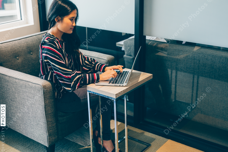 High angle view of businesswoman sitting on sofa with laptop