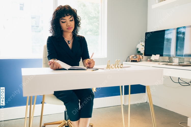 Direct view of left handed young businesswoman writing in diary