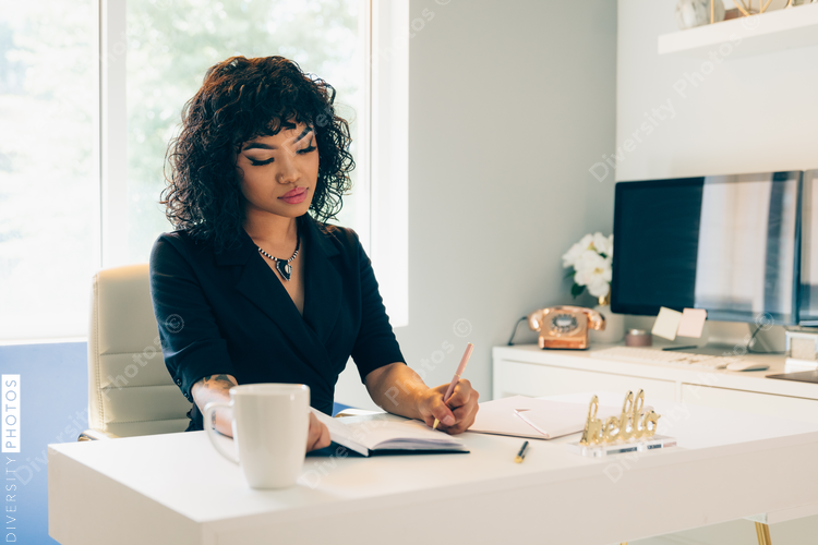 Direct view of left handed young businesswoman writing in diary