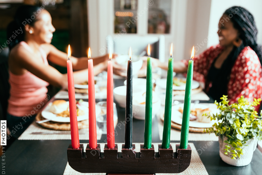 Women seated behind lighted Kwanzaa candles
