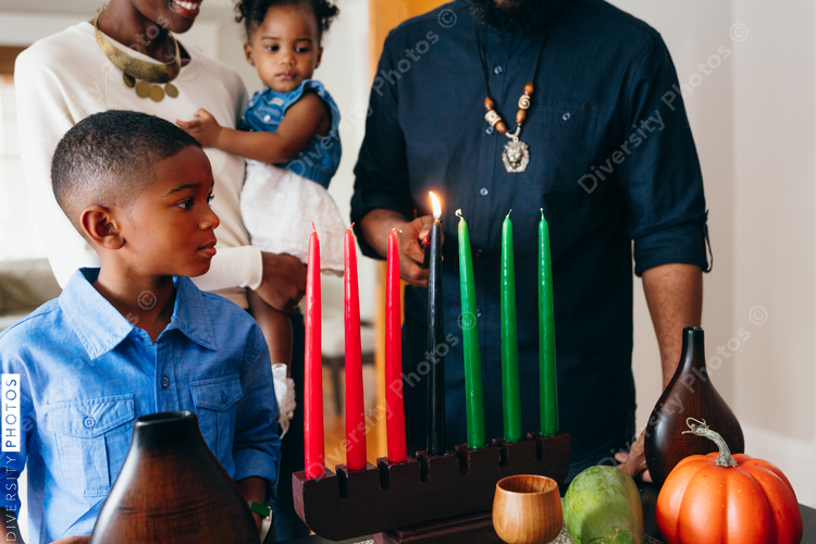 Man lighting candle to celebrate Kwanzaa with family