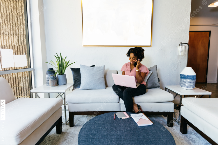 Businesswoman talking on mobile phone while using laptop