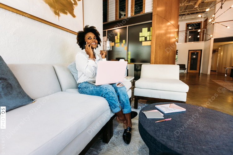 Low angle view of woman talking on mobile phone with laptop