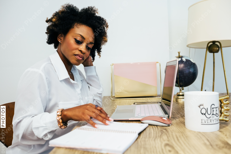 Woman going through notes with laptop beside