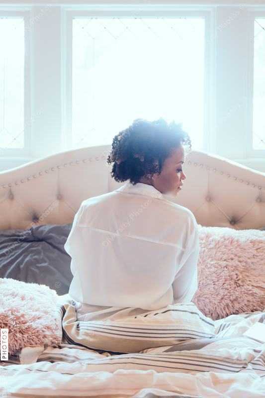 Back view of woman sitting on bed