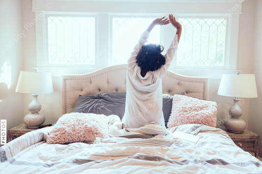 Back view of woman stretching her hands in bed