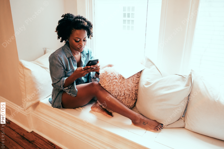 Woman sitting on windowsill using mobile phone
