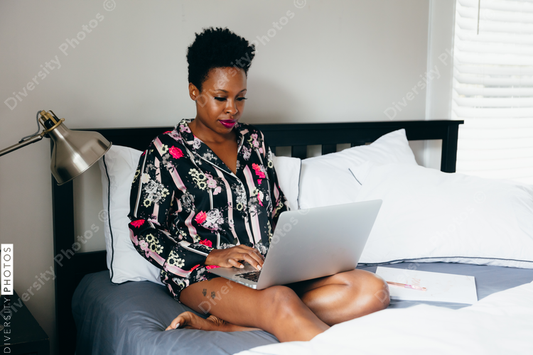 Woman working on laptop in her bed