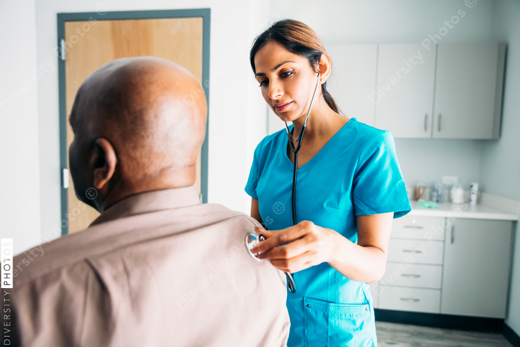 Nurse listening to stethoscope on patient's back