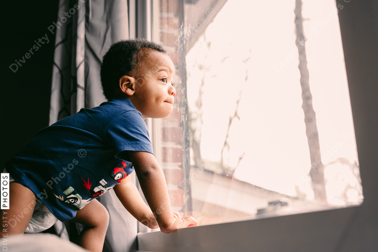 Young toddler looking out the window at home