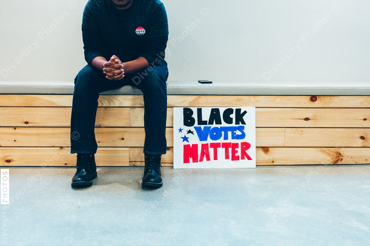 Person sitting with their Black Votes Mstter sign
