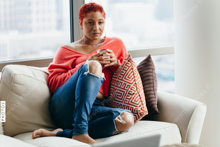 Black woman relaxing and drinking tea at home on couch