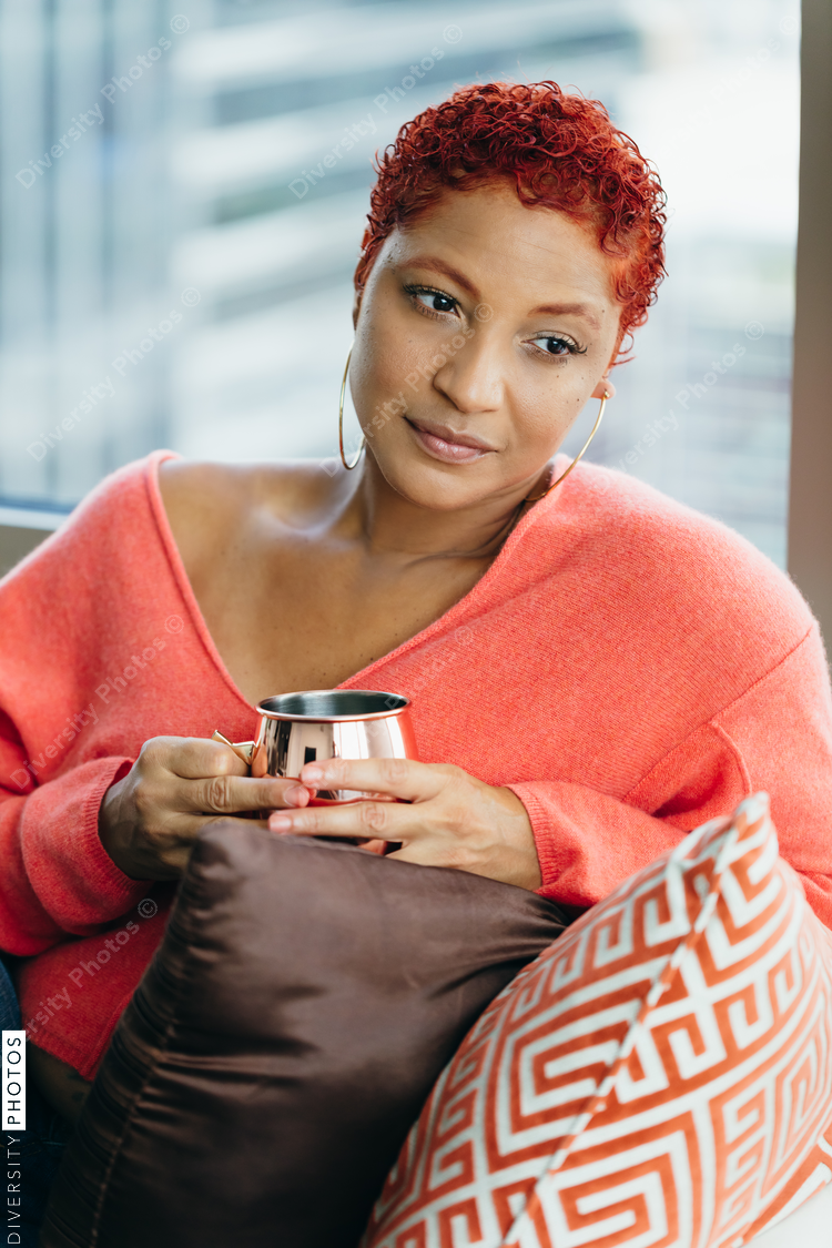 Black woman relaxing and drinking tea at home on couch