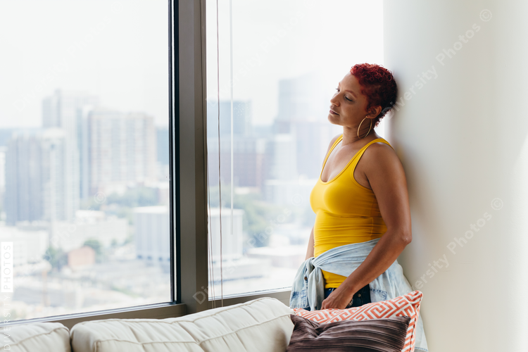 Woman looking out window thinking and reflecting at home
