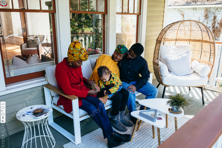 Black family enjoying time together outside on the front porch with young child