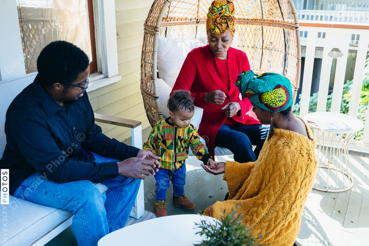Multigenerational Black family enjoying time together outside on the front porch with young child
