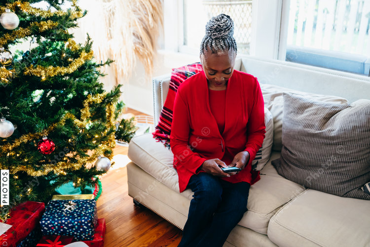 Senior Black woman with grey hair looking at phone on Christmas morning