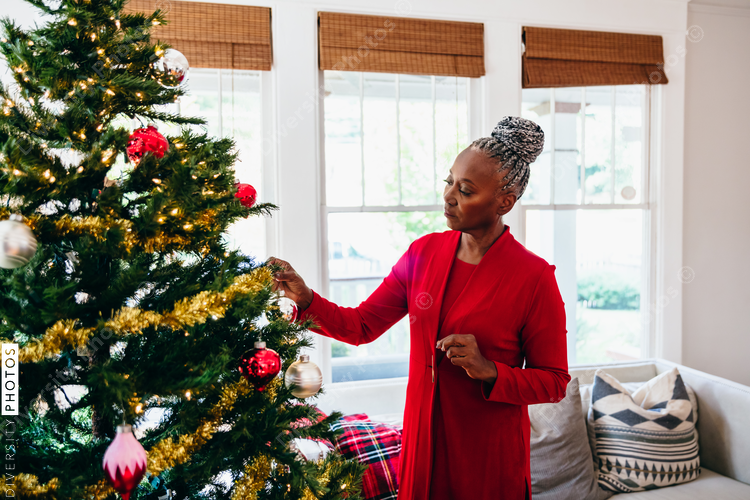 Senior Black woman decorating the Christmas tree with ornaments