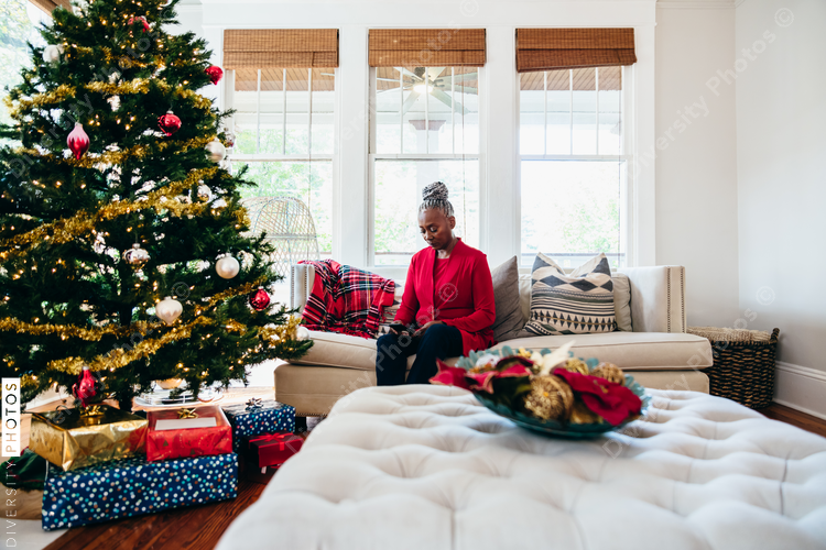 Senior Black woman sitting on sofa and reading for Christmas