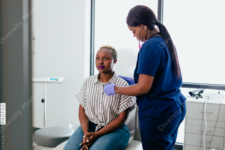 Black nurse takes vitals of black female patient in exam room at medical facility