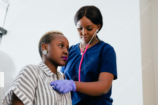 Black nurse listening to heart and breathing of woman patient