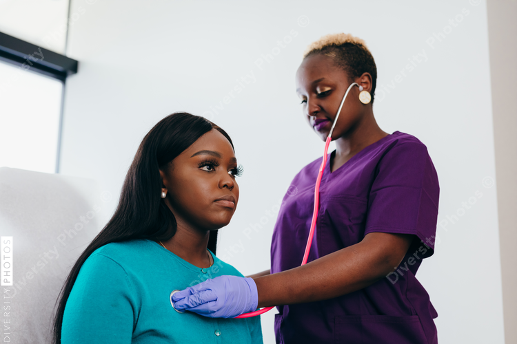 Black nurse listening to heart and breathing of woman patient