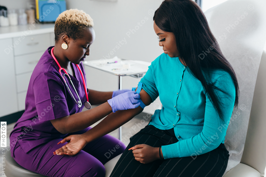Black nurse collects blood sample from female patient at doctors office