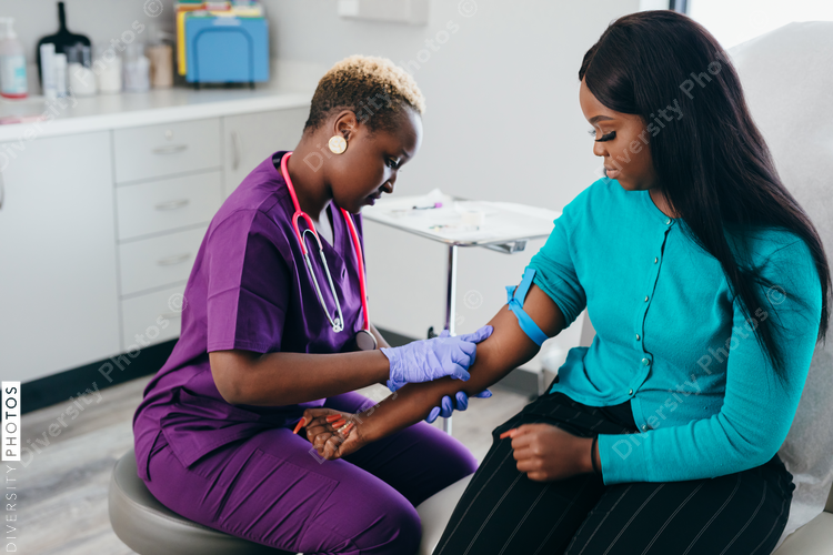 Black nurse collects blood sample from female patient at doctors office