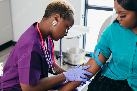 Black nurse collects blood sample from female patient at doctors office