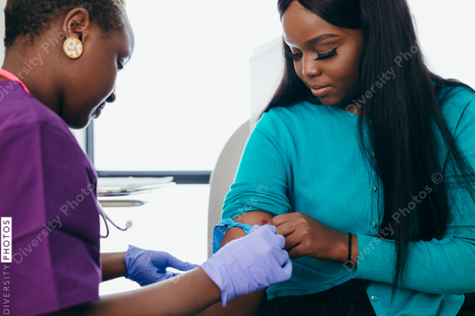 Black nurse collects blood sample from female patient at doctors office