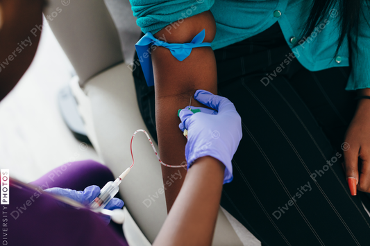 Black nurse collects blood sample from female patient at doctors office