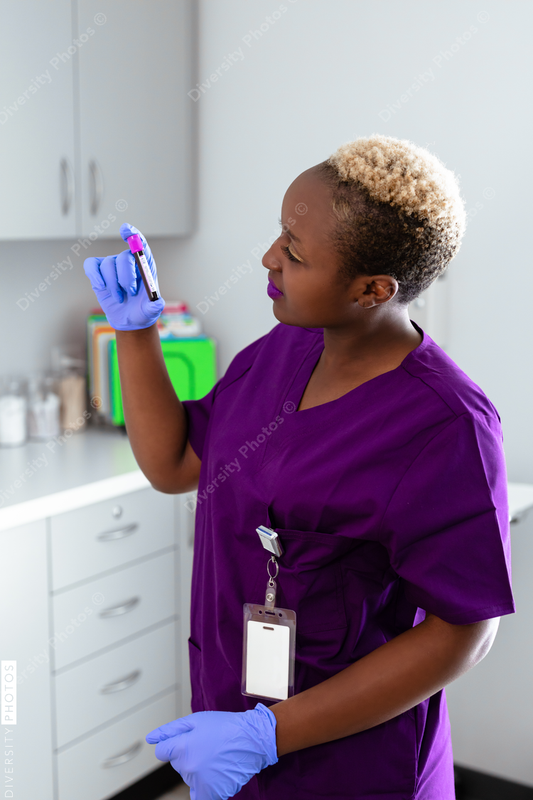 Black female nurse reading blood sample label at medical office