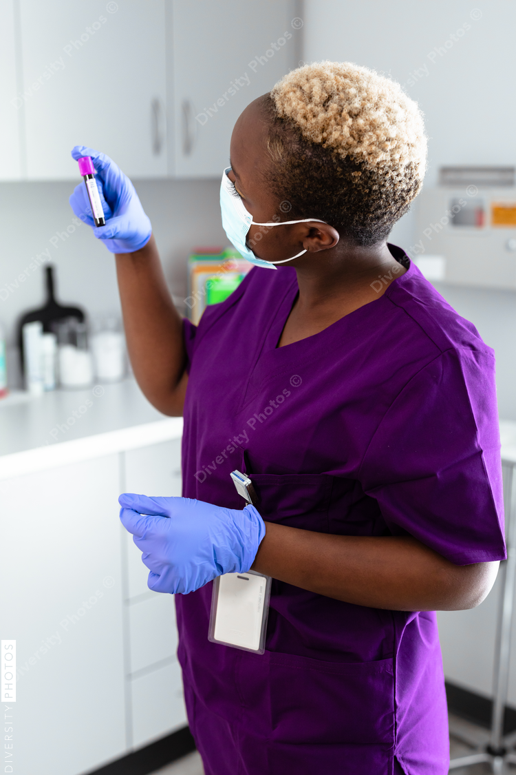 Black female nurse reading blood sample label at medical office
