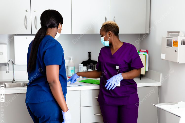 Two black nurse having conversation in doctors office exam room