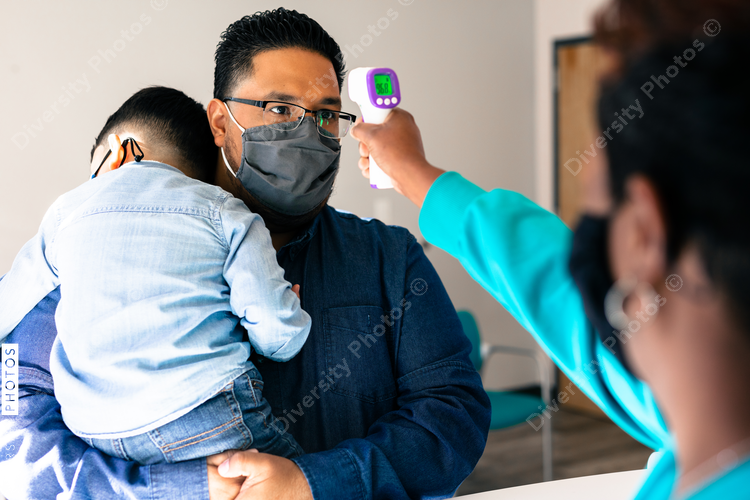 Nusing taking temperature of hispanic father and son at doctor office