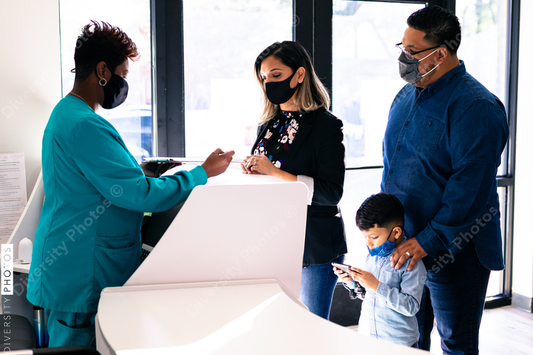 Black nurse reviewing medical forms with Latino family at doctor office