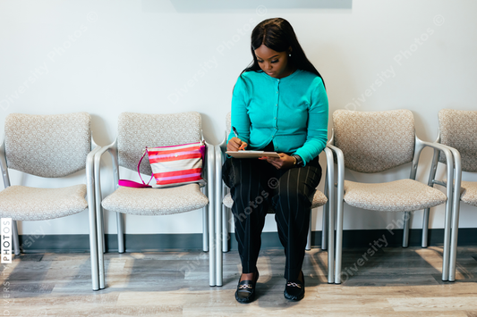 Black woman completing medical paperwork at doctor office in waiting room
