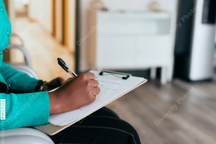 Black woman completing medical paperwork and healthcare forms on clipboard