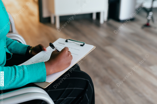 Black woman completing medical paperwork and healthcare forms on clipboard