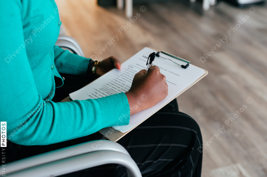 Black woman completing medical paperwork and healthcare forms on clipboard