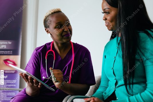Black nurse reviewing information digitally on tablet with patient at medical facility