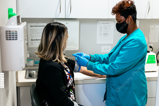 Black nurse draws blood from hispanic woman at medical facility