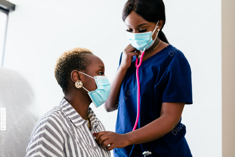 Black nurse takes vitals of black female patient in exam room at medical facility