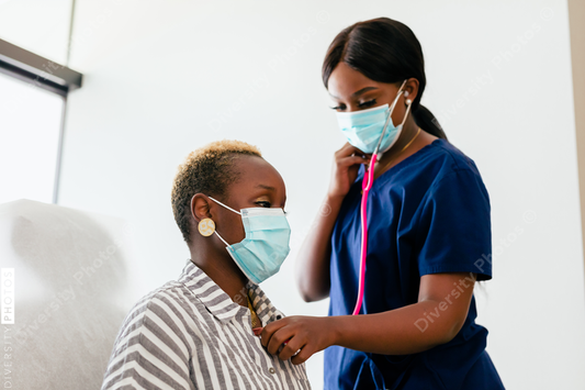 Black nurse takes vitals of black female patient in exam room at medical facility