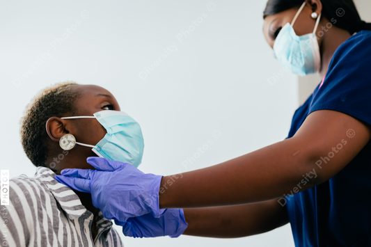 Black nurse takes vitals of black female patient in exam room at medical facility