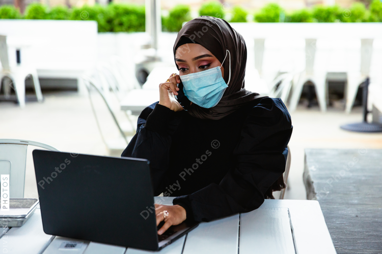 Professional Muslim businesswoman working remote at local coffee shop