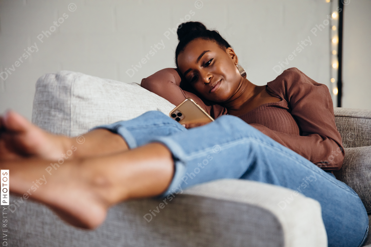 Black woman relaxing and comfortable on couch looking at cellphone
